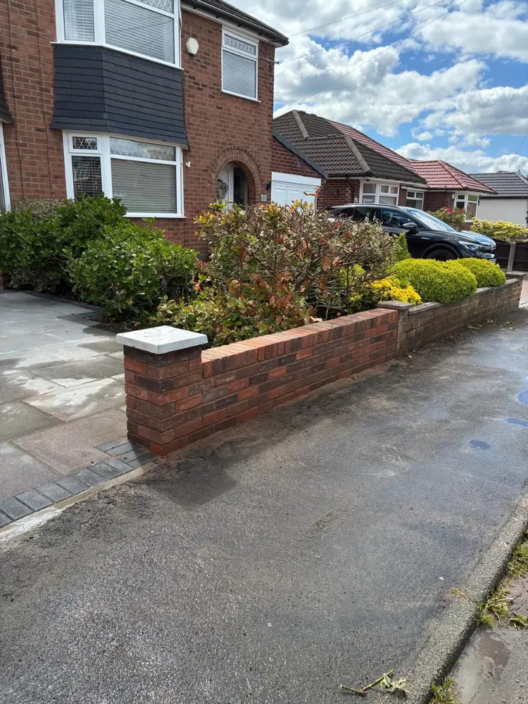 Completed low red brick front wall with coping, alongside a driveway in Manchester